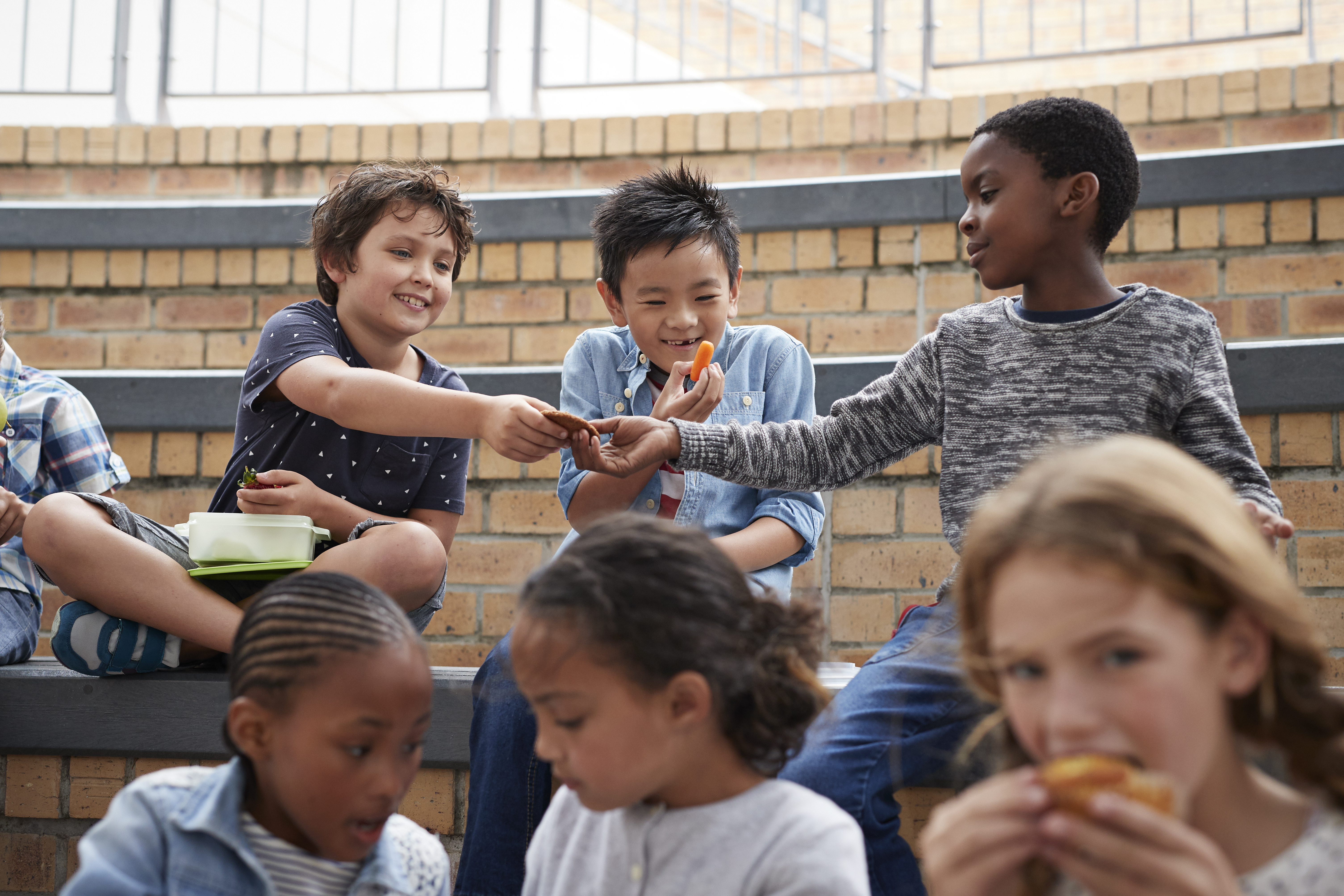 A group of children sitting together, laughing and eating lunch