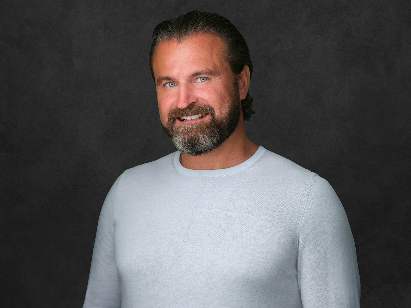 Jason Smith smiling and wearing a long-sleeve light grey top