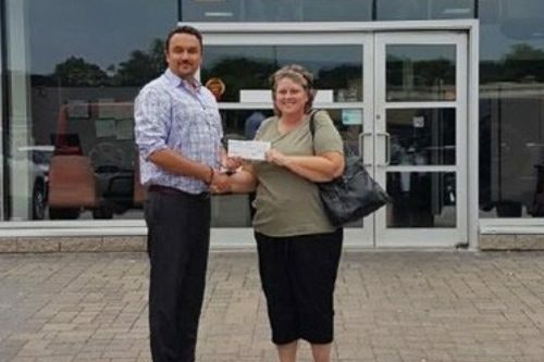 Photo of contest winner Sharon Benson holding cheque and posing with Go Auto staff member